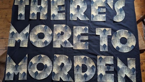 A blue quilt with the words 'Made in Morden' stitched on the front.